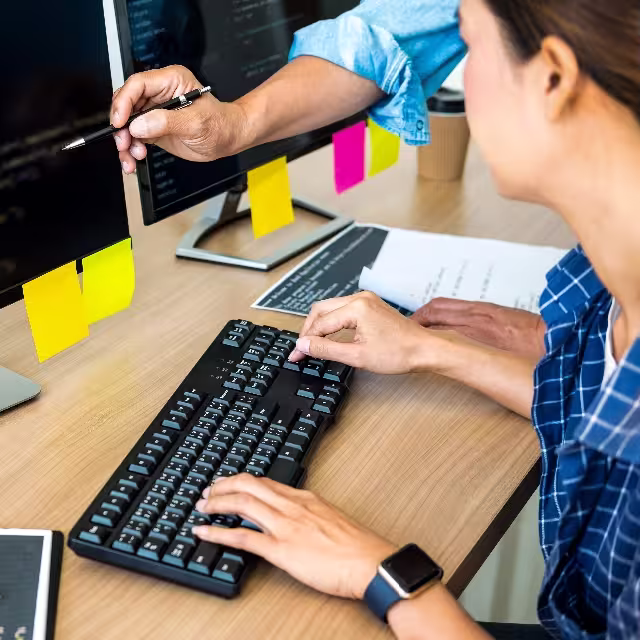 Woman typing on a keyword, an arm reaches in to point to something on the screen