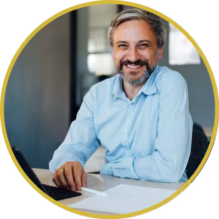 Middle aged man in a collared shirt with a laptop smiling at the camera
